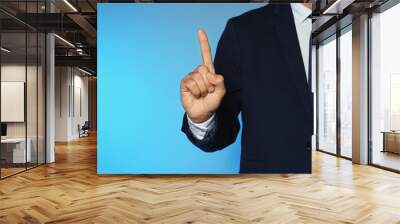 Businessman pointing on color background, closeup view of hand with space for text Wall mural