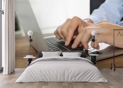 Businessman using laptop at wooden table, closeup. Modern technology Wall mural