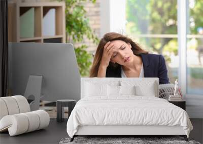 Businesswoman suffering from heat in front of small fan at workplace Wall mural