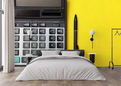 Calculator and pen on yellow background, flat lay. Space for text Wall mural