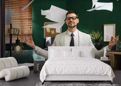 Calm businessman meditating at office desk in middle of busy work day Wall mural