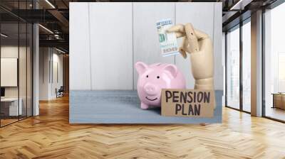 Card with phrase Pension Plan, mannequin hand holding dollar banknote and piggy bank on light blue wooden table, space for text. Retirement concept Wall mural