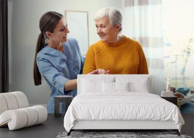 Care worker helping elderly woman to walk in geriatric hospice Wall mural