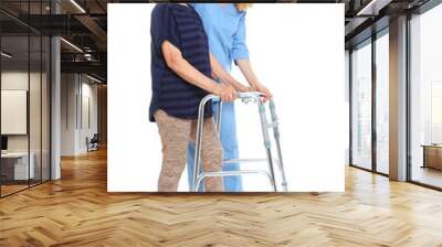 Caretaker helping elderly woman with walking frame on white background Wall mural