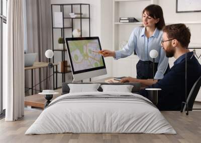 Cartographers working with cadastral map on computer at table in office Wall mural