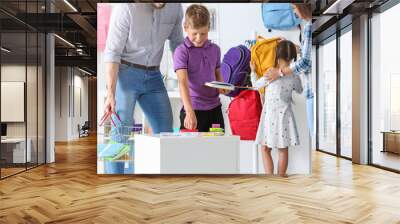 Children with parents choosing school stationery in store Wall mural