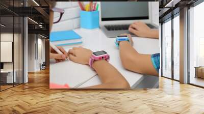 Children with stylish smart watches at white table, closeup Wall mural