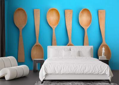 Clean empty wooden spoons on blue background, flat lay Wall mural