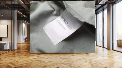 Clothing label on pale olive garment, closeup Wall mural