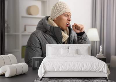 Cold symptom. Young man in winter coat coughing at home Wall mural