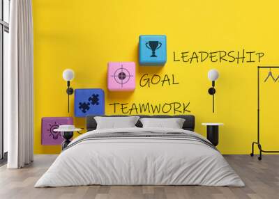 Colorful cubes with different images and words Leadership, Goal, Teamwork and Solution on yellow background, flat lay Wall mural