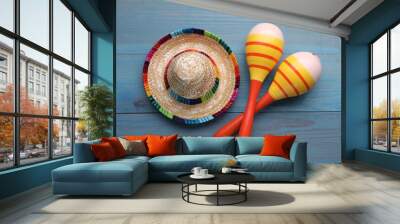 Colorful maracas and sombrero hat on light blue wooden table, flat lay. Musical instrument Wall mural