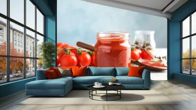 Composition with jar of tasty tomato sauce on table against color background Wall mural