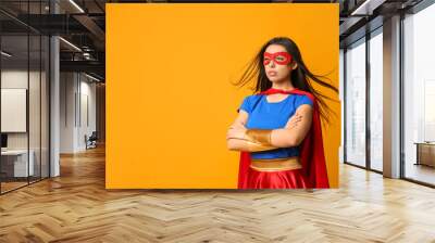 Confident young woman wearing superhero costume on orange background, space for text Wall mural