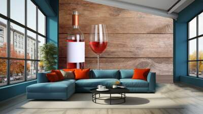 Corkscrew near bottle and glass of delicious rose wine on table against wooden background. Space for text Wall mural