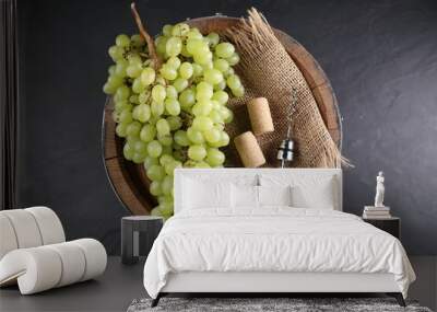 Corkscrew with metal handle, corks, grapes and wooden barrel on grey table, top view Wall mural