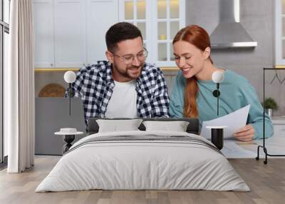 Couple calculating taxes for online payment at table in kitchen Wall mural