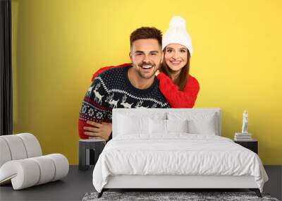 Couple wearing Christmas sweaters on yellow background Wall mural