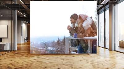 Couple with backpacks enjoying mountain view during winter vacation. Space for text Wall mural