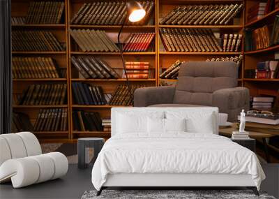 Cozy home library interior with comfortable armchair and collection of vintage books on shelves Wall mural