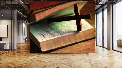 Cross and Bible on wooden table in color lights, closeup. Religion of Christianity Wall mural