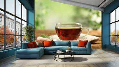 Cup of black tea on wooden table against blurred background. Space for text Wall mural