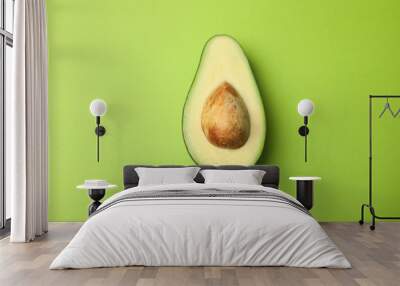 Cut fresh ripe avocado on green background, top view Wall mural