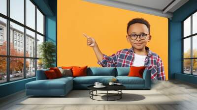 Cute African-American boy with glasses pointing on orange background. Space for text Wall mural