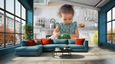 Cute African-American girl with plate of vegetables at table in kitchen Wall mural