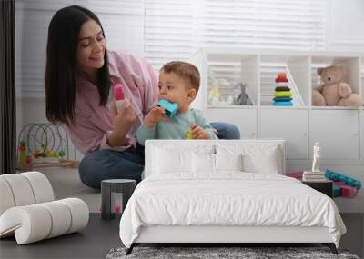 Cute baby boy playing with mother and building blocks on floor at home Wall mural