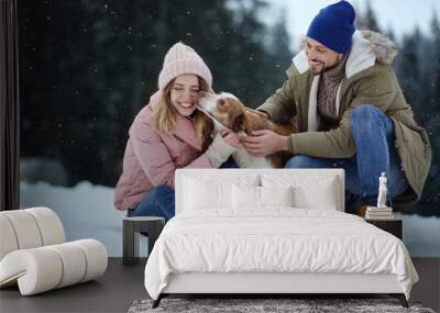 Cute couple with dog near forest. Winter vacation Wall mural