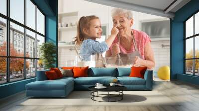 Cute girl and her grandmother cooking in kitchen Wall mural