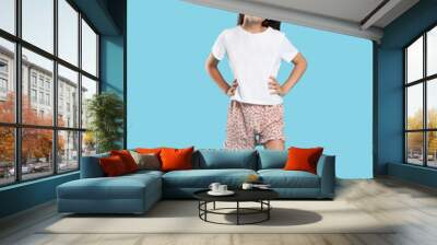 Cute girl wearing pajamas on light blue background Wall mural