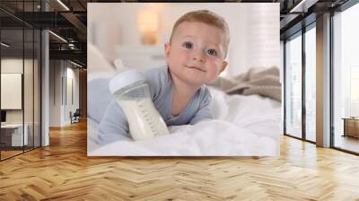 Cute little baby with bottle of milk on bed indoors Wall mural