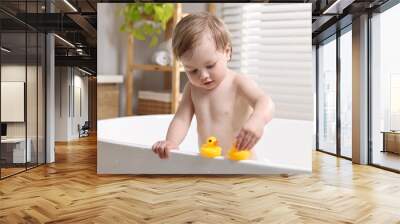 Cute little child playing with toy ducks in bathtub at home Wall mural