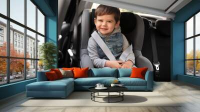 Cute little child sitting in safety seat inside car. Danger prevention Wall mural