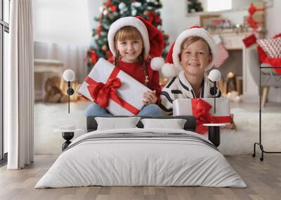 Cute little children in Santa hats with Christmas gift boxes at home Wall mural