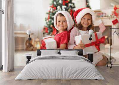 Cute little children in Santa hats with Christmas gift boxes at home Wall mural