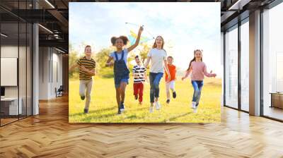 Cute little children playing with kite outdoors on sunny day Wall mural