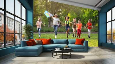 Cute little children playing with kite outdoors on sunny day Wall mural