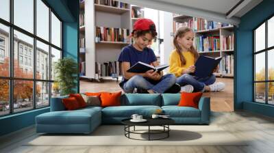 Cute little children reading books on floor in library Wall mural