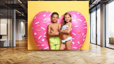 Cute little children with bright heart shaped inflatable ring near color wall Wall mural