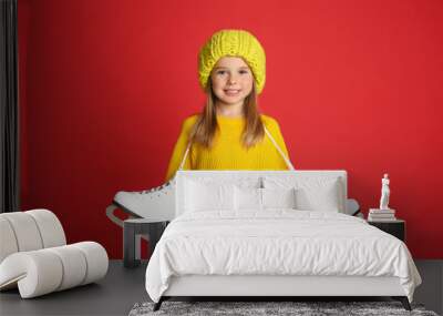 Cute little girl in yellow knitted sweater with skates on red background Wall mural