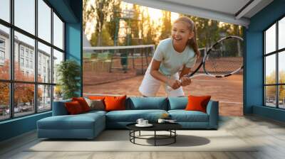 Cute little girl playing tennis on court outdoors Wall mural