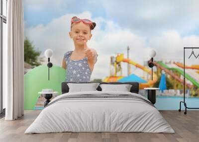 Cute little girl with inflatable ring near pool in water park, space for text Wall mural