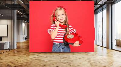 Cute little girl with telephone on red background Wall mural