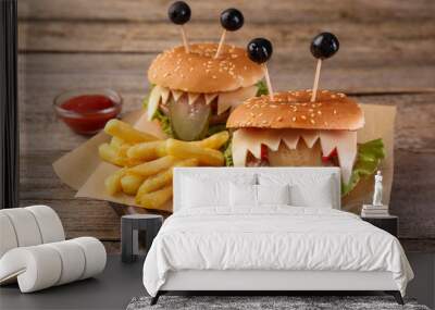 Cute monster burgers served with french fries and ketchup on wooden table. Halloween party food Wall mural