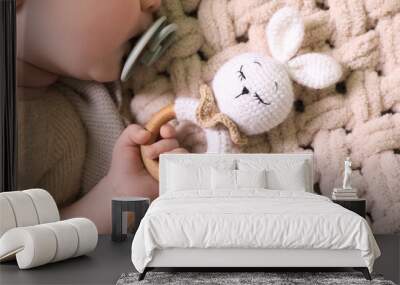 Cute newborn baby with pacifier and toy bunny on beige crocheted plaid, top view Wall mural