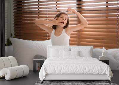 Cute preteen girl awakening on bed near window Wall mural