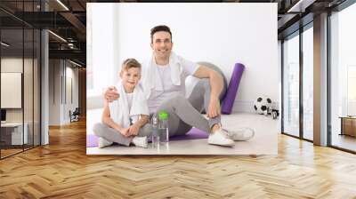 Dad and his son with bottles of water in gym Wall mural